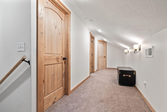 hallway with a textured ceiling, carpet flooring, lofted ceiling, and baseboards