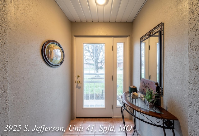 doorway with tile patterned flooring and a textured wall