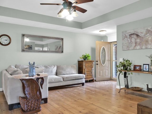 living room featuring a tray ceiling, hardwood / wood-style flooring, and a ceiling fan