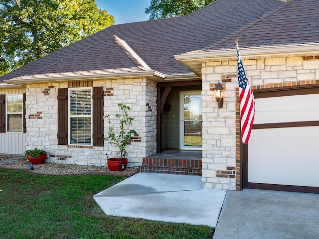 entrance to property featuring a garage and a shingled roof