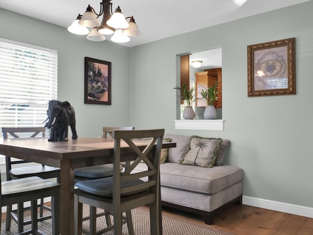 dining area featuring a chandelier, baseboards, and wood finished floors