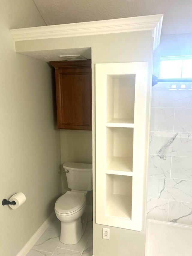 bathroom with baseboards, built in features, toilet, ornamental molding, and marble finish floor