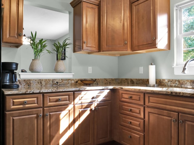 kitchen featuring brown cabinetry and light stone counters