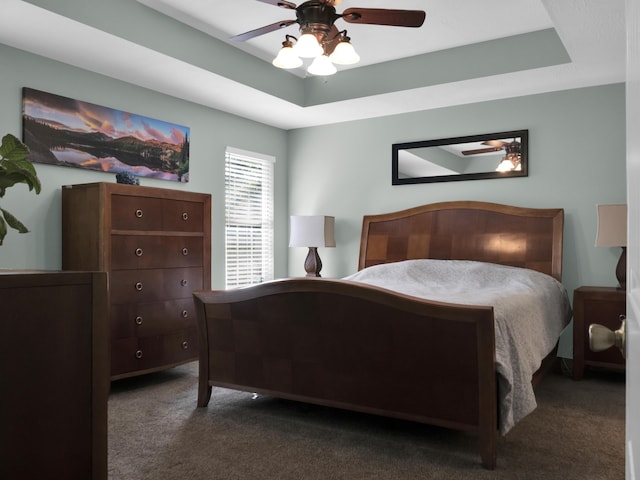 carpeted bedroom with a ceiling fan and a raised ceiling