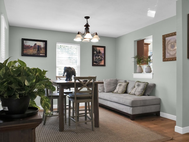 dining space with a chandelier, baseboards, and wood finished floors