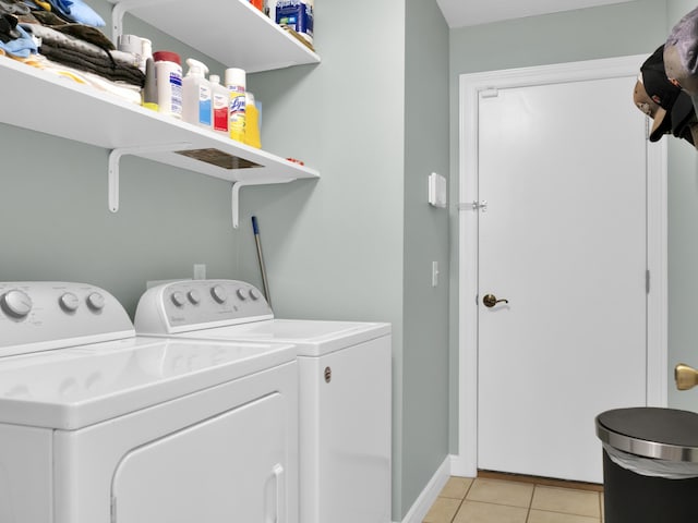 laundry area with laundry area, light tile patterned flooring, washing machine and clothes dryer, and baseboards