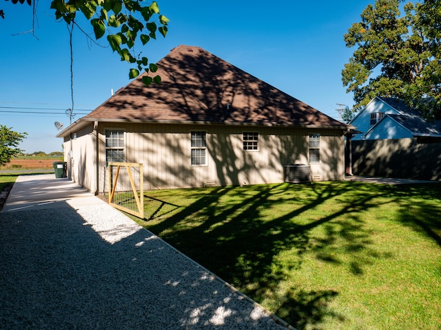 exterior space featuring a shingled roof, gravel driveway, and a yard