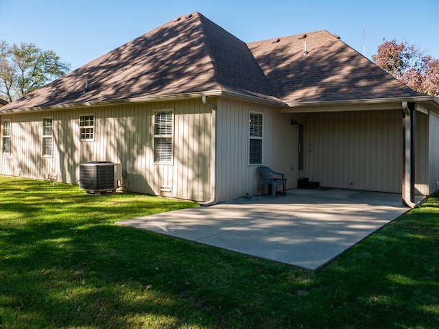 rear view of house with roof with shingles, central AC, a lawn, and a patio