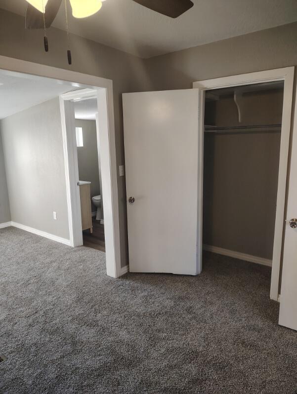 unfurnished bedroom featuring carpet floors, a closet, ceiling fan, and baseboards