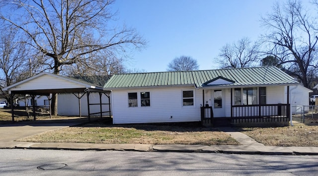 view of front of property featuring metal roof, a carport, a porch, and concrete driveway