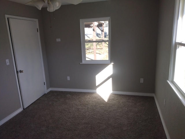 carpeted spare room featuring a healthy amount of sunlight, baseboards, and a ceiling fan