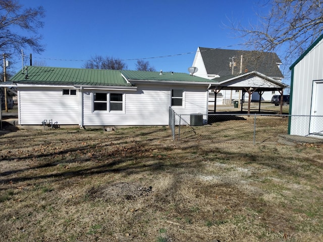 view of property exterior with central air condition unit, fence, metal roof, and a lawn