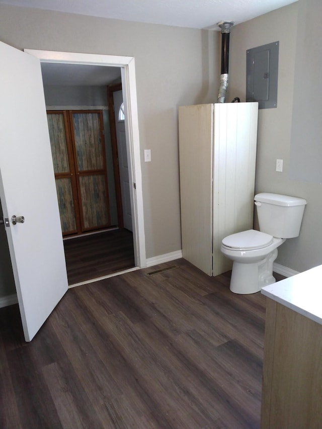 bathroom featuring toilet, electric panel, baseboards, and wood finished floors