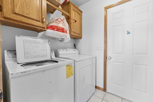 clothes washing area with cabinet space, washer and clothes dryer, baseboards, and light tile patterned flooring