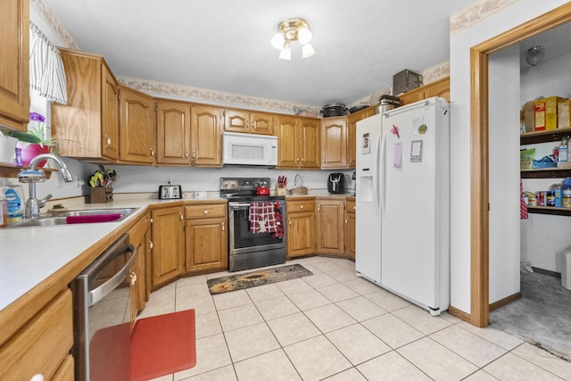 kitchen with stainless steel appliances, brown cabinetry, a sink, and light countertops