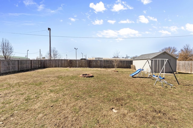 view of yard with a fire pit, a playground, and a fenced backyard