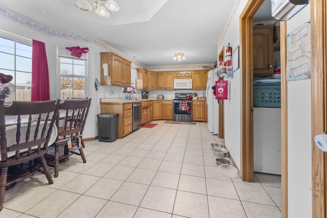 kitchen with light tile patterned floors, a sink, light countertops, appliances with stainless steel finishes, and brown cabinetry