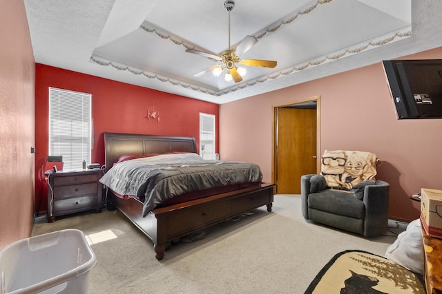 carpeted bedroom featuring a ceiling fan and a raised ceiling