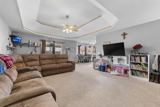 carpeted living area featuring a tray ceiling and a ceiling fan