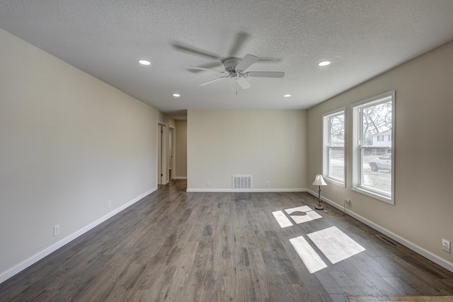 spare room featuring visible vents, a textured ceiling, baseboards, and wood finished floors