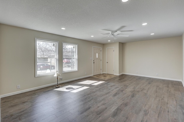 empty room with a textured ceiling, wood finished floors, visible vents, and baseboards