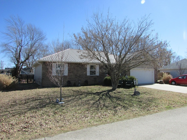 ranch-style house featuring a garage, concrete driveway, metal roof, and a front yard