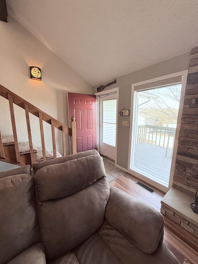 living room featuring lofted ceiling, a textured ceiling, and visible vents