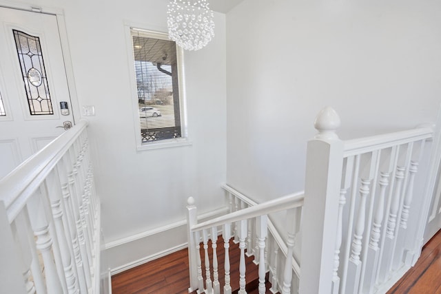 stairs featuring baseboards, an inviting chandelier, and wood finished floors