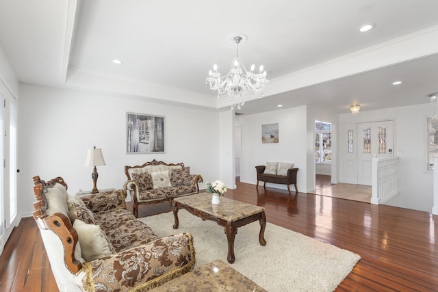 living area with an inviting chandelier, wood-type flooring, a raised ceiling, and recessed lighting