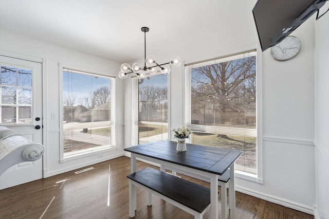 dining space featuring a chandelier, visible vents, baseboards, and wood finished floors