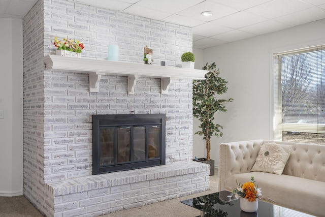 interior details featuring carpet floors, a brick fireplace, and a drop ceiling