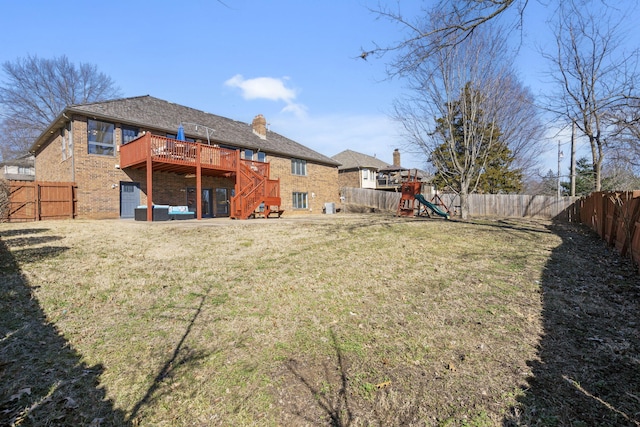 back of property with brick siding, a fenced backyard, a playground, and a yard