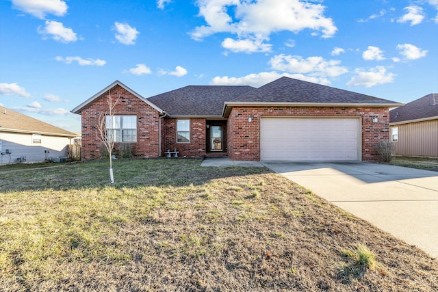 single story home featuring a shingled roof, concrete driveway, an attached garage, a front yard, and brick siding