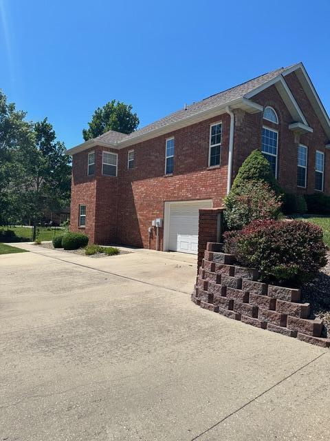 view of front of property featuring driveway, a garage, and brick siding