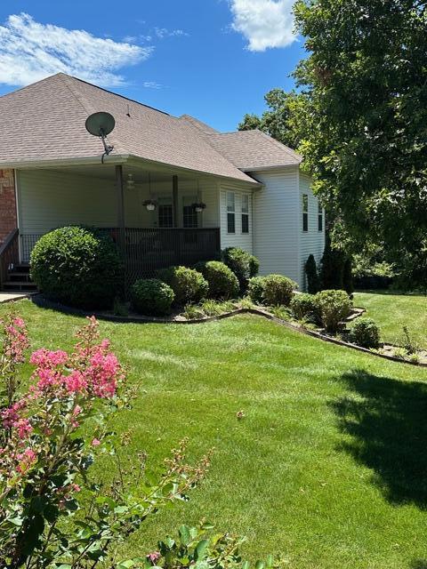 rear view of property featuring roof with shingles and a yard