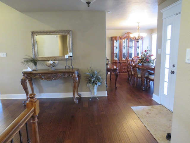 foyer entrance featuring a chandelier, baseboards, and wood finished floors