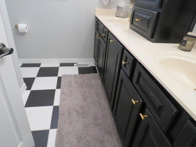 bathroom featuring baseboards, double vanity, visible vents, and tile patterned floors