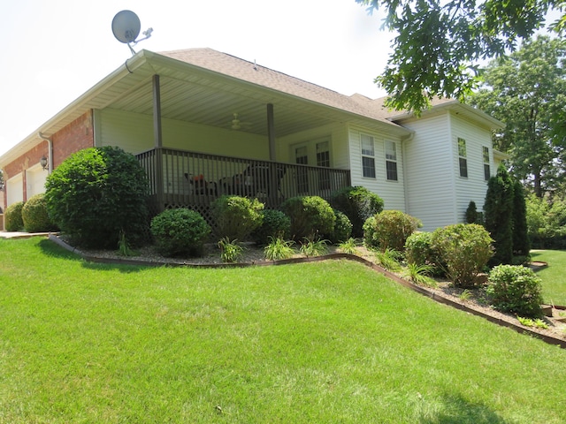 rear view of house with a garage, ceiling fan, and a lawn