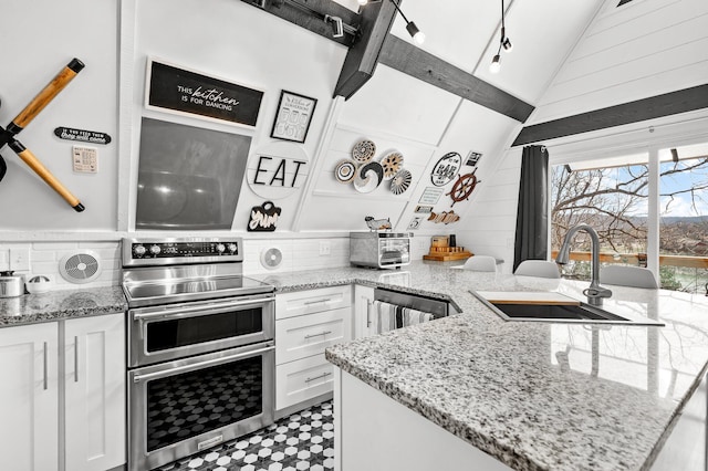 kitchen featuring range with two ovens, light floors, lofted ceiling, white cabinets, and a sink