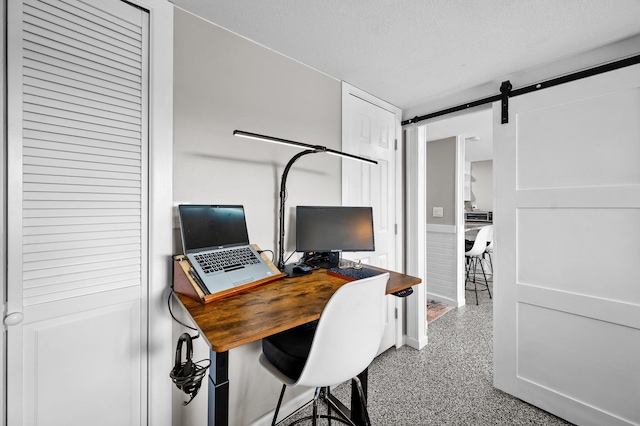 office area featuring speckled floor, a textured ceiling, and a barn door