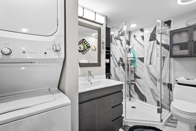 full bath featuring stacked washer and dryer, a shower stall, toilet, and vanity