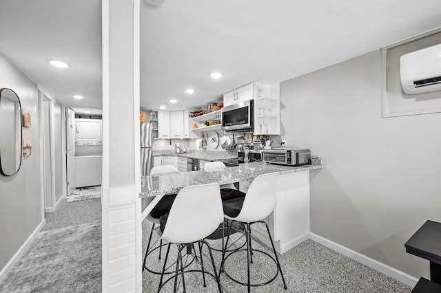 kitchen featuring light stone counters, white cabinets, stacked washer / drying machine, appliances with stainless steel finishes, and open shelves