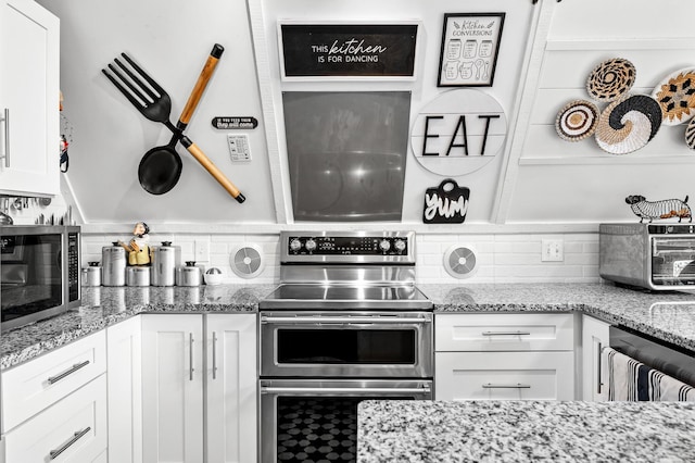 kitchen with white cabinets, light stone countertops, stainless steel appliances, and backsplash