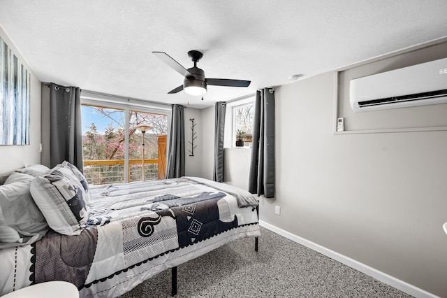 bedroom featuring a ceiling fan, a textured ceiling, baseboards, and an AC wall unit