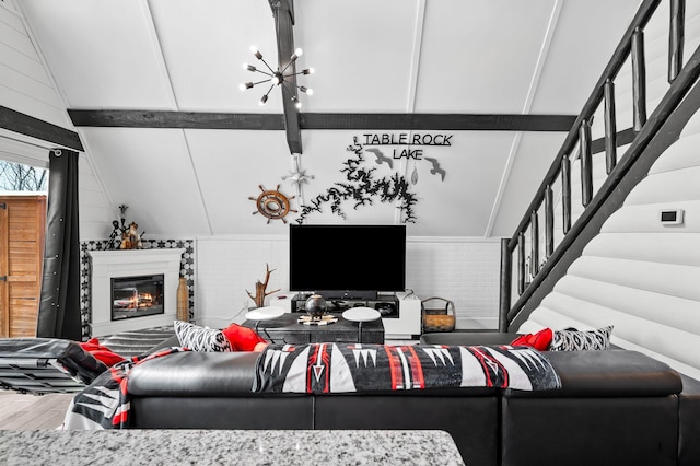 living area featuring a glass covered fireplace, wood finished floors, vaulted ceiling, and stairs