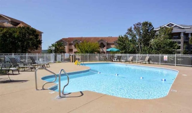 pool with a patio area and fence