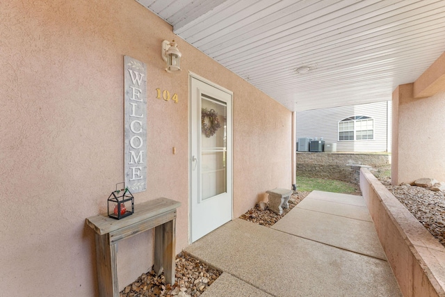 doorway to property with cooling unit and stucco siding