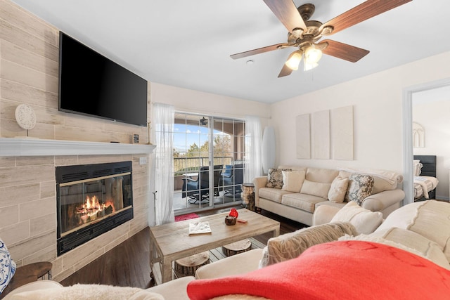 living room featuring ceiling fan, a tiled fireplace, and wood finished floors