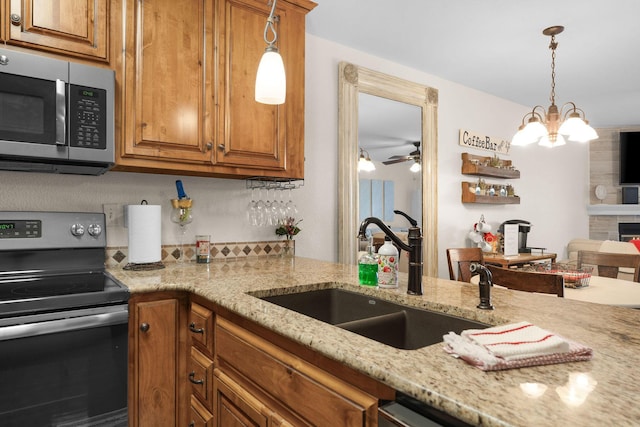 kitchen with brown cabinetry, light stone counters, stainless steel appliances, and a sink