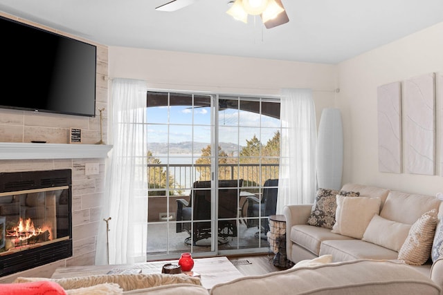 living area with ceiling fan and a fireplace